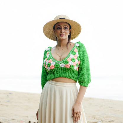 Woman wearing a green crochet top with floral patterns against a natural background