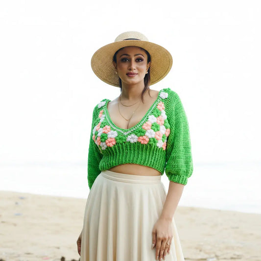 Woman wearing a green crochet top with floral patterns against a natural background