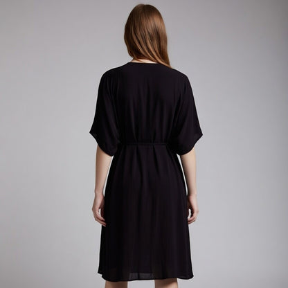 Woman wearing a black dress against a grey background