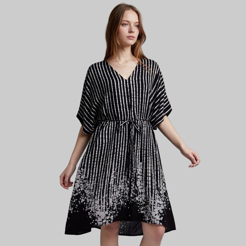 Woman wearing a black and white patterned dress on a grey background