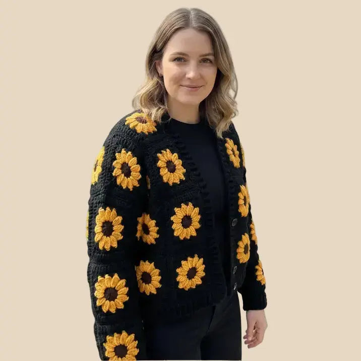 Woman wearing a black crochet cardigan with yellow sunflower patterns on a beige background
