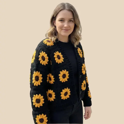 Woman wearing a black crochet cardigan with yellow sunflower patterns on a beige background