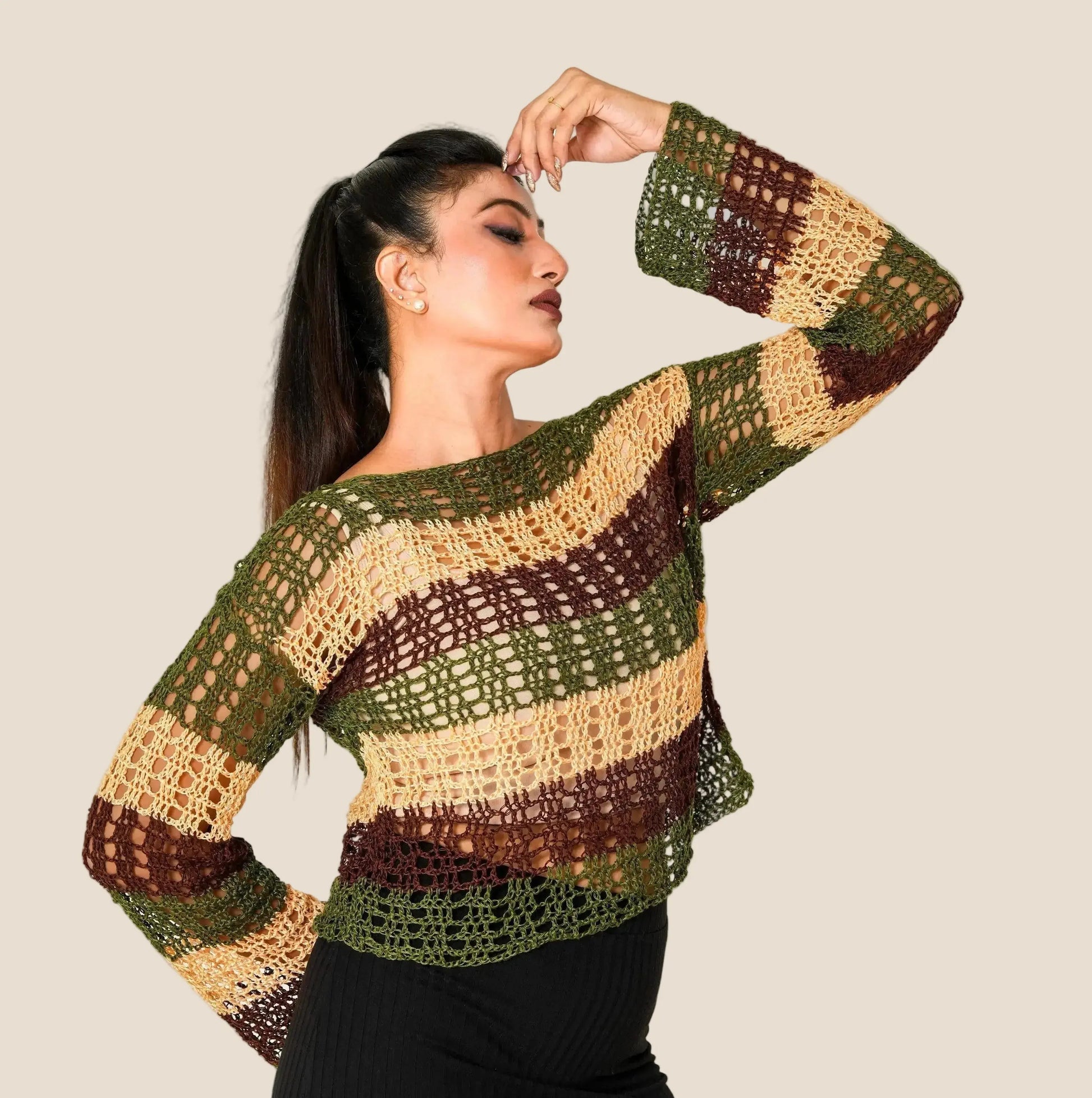 Woman wearing a crocheted sweater with a neutral background