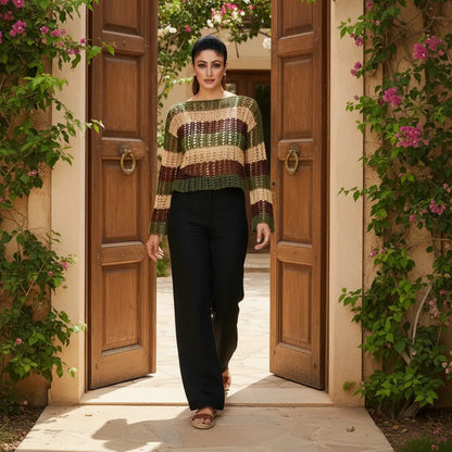 Woman in a patterned sweater and black pants standing in an open wooden door with floral decorations.