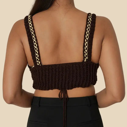 Woman wearing a brown crochet top with strap details on a plain background