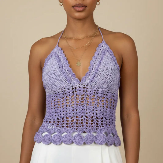 A woman wearing a lavender purple crochet halter top with a scalloped V-neckline and pom-pom hem, paired with a white skirt against a beige background-Veyaro