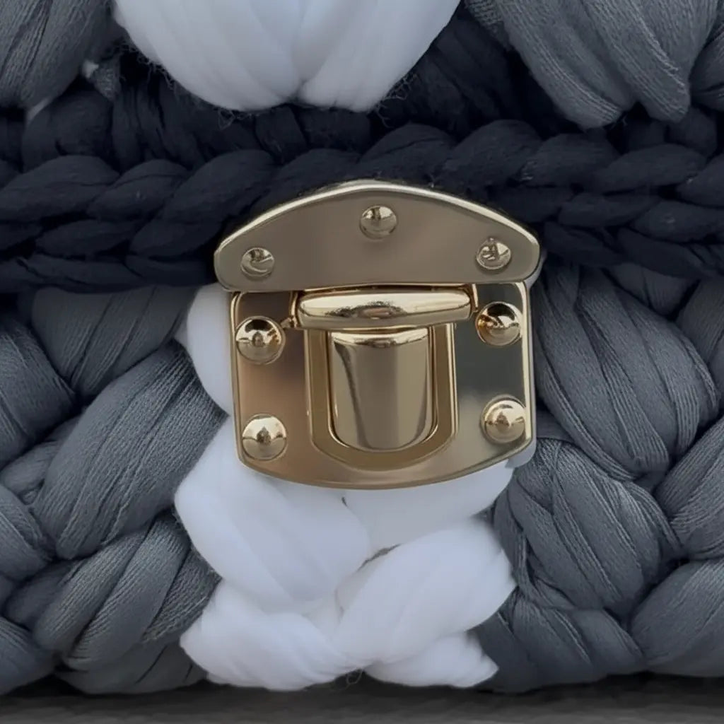 Close-up of braided fabric with a gold buckle on a gray background