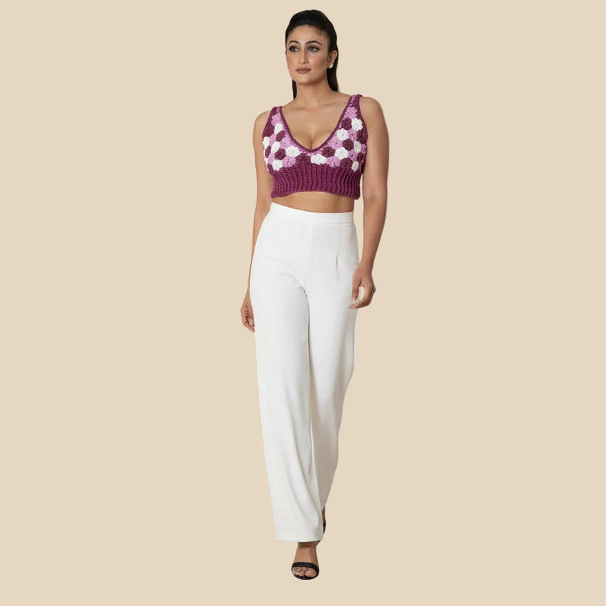 Woman wearing a white pant and purple floral top in a minimal indoor setting