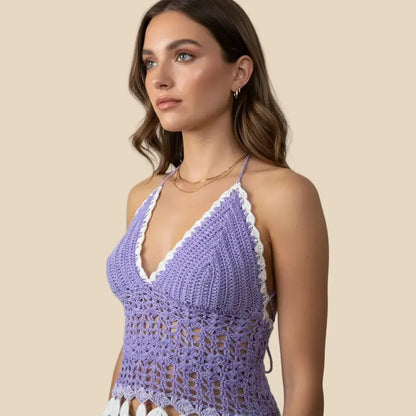 Woman wearing a purple crochet top with white trim against a plain background