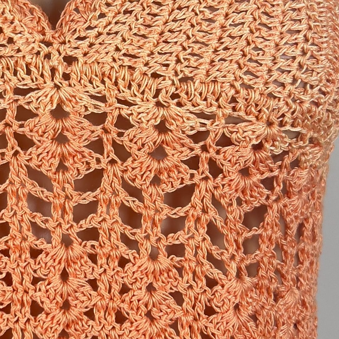 Close-up of a handcrafted crocheted orange fabric with intricate pattern