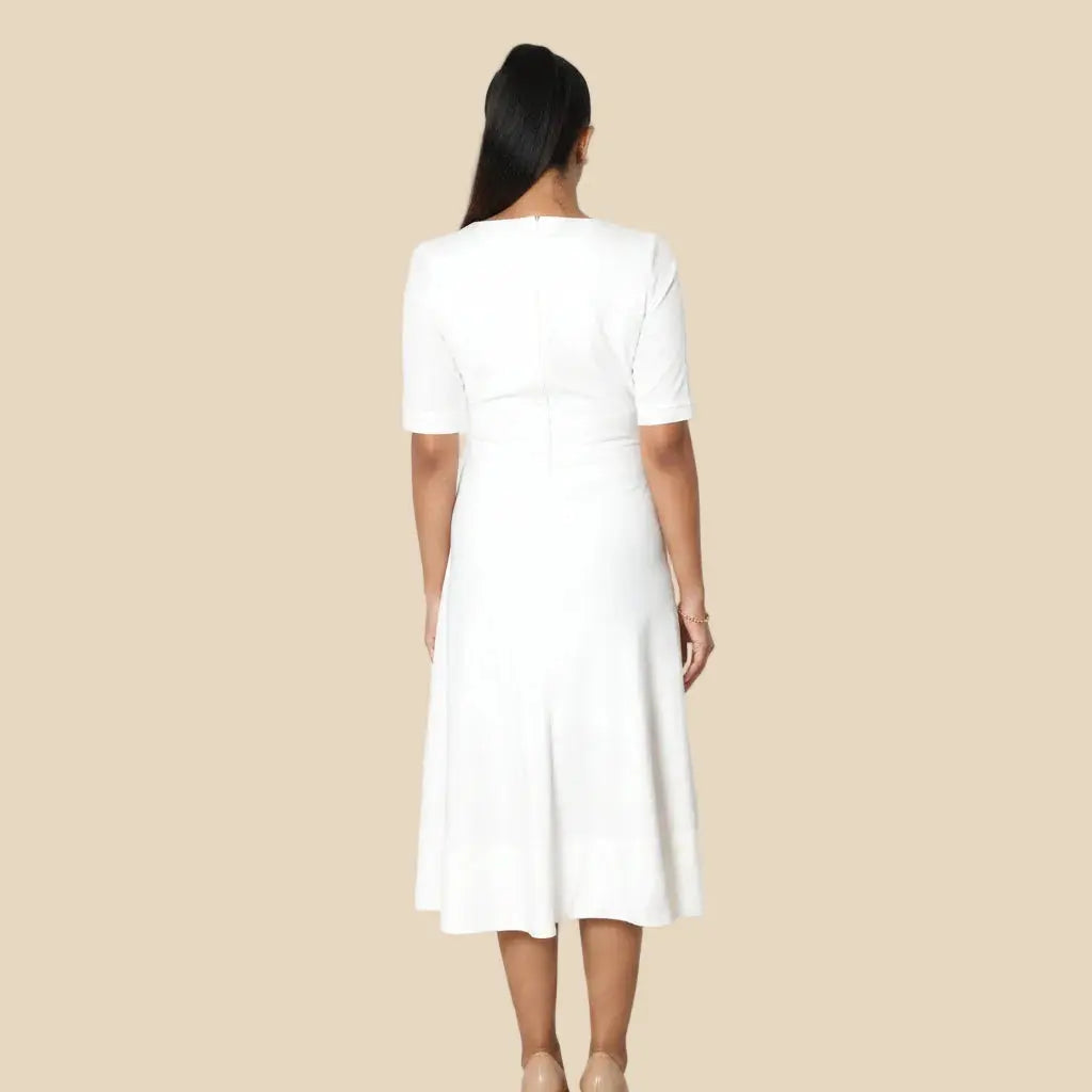 Person wearing a white dress standing on a tiled floor.