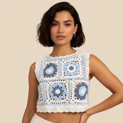 A woman wearing a sleeveless veyaro-crocheted crop top with blue and white granny square patterns, posed against a solid beige background.