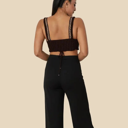 Person wearing a brown crop top and black pants on a beige background