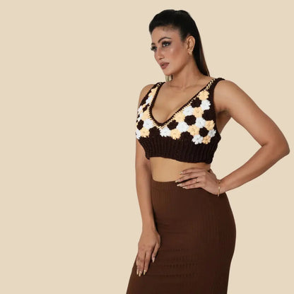 Woman wearing a black and white floral top with a brown skirt on a beige background