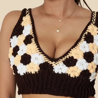 Woman wearing a brown crochet top with floral patterns on a plain background